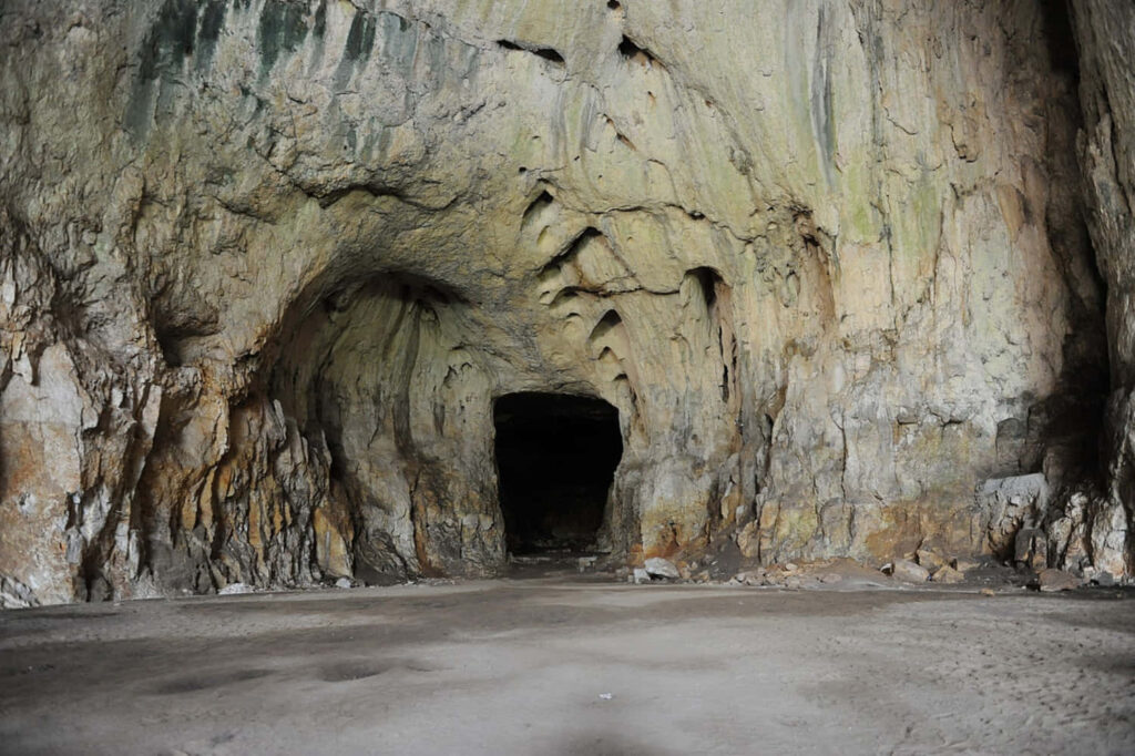 Majestic Cave View: Rugged Walls & Enigmatic Light Play Wallpaper
