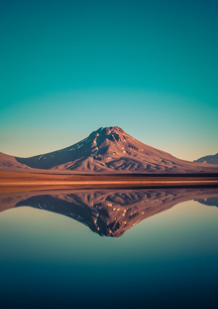 Majestic Chilean mountain reflected in tranquil laguna with clear blue sky and earthy tones Wallpaper