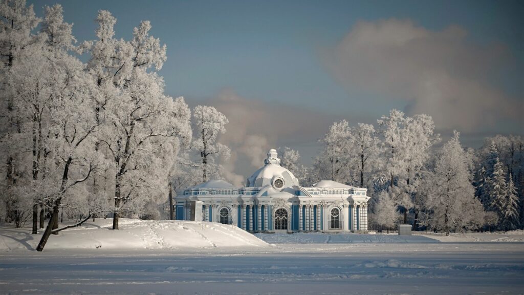 Majestic classical building in snowy winter landscape with snow-covered trees and blue sky background Wallpaper