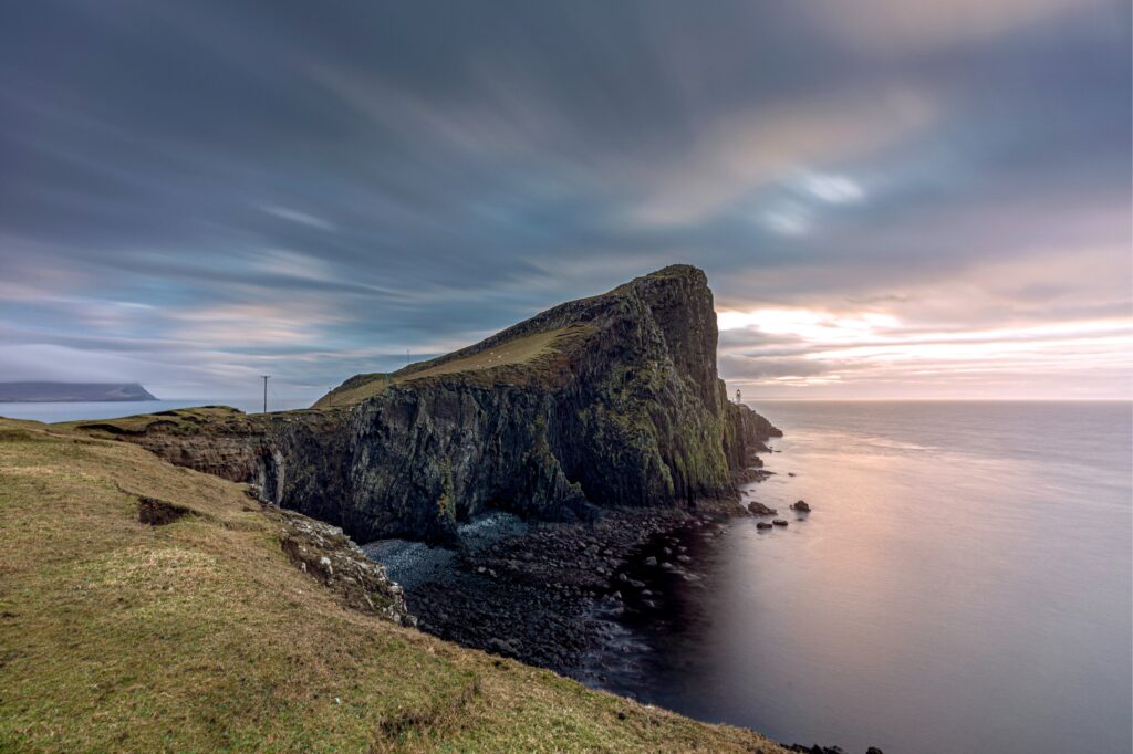 Majestic cliff over rugged coastline with calm sea and moody sky creating tranquil landscape wallpaper