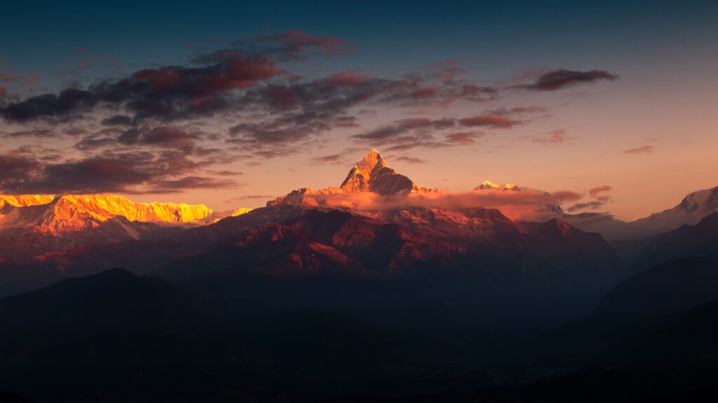 Majestic Himalayas with rugged peaks glowing in golden light under dramatic cloudy sky wallpaper