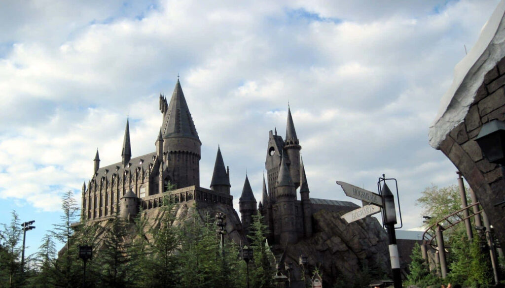Hogwarts Castle under dramatic clouds with gothic towers and lush greenery wallpaper background