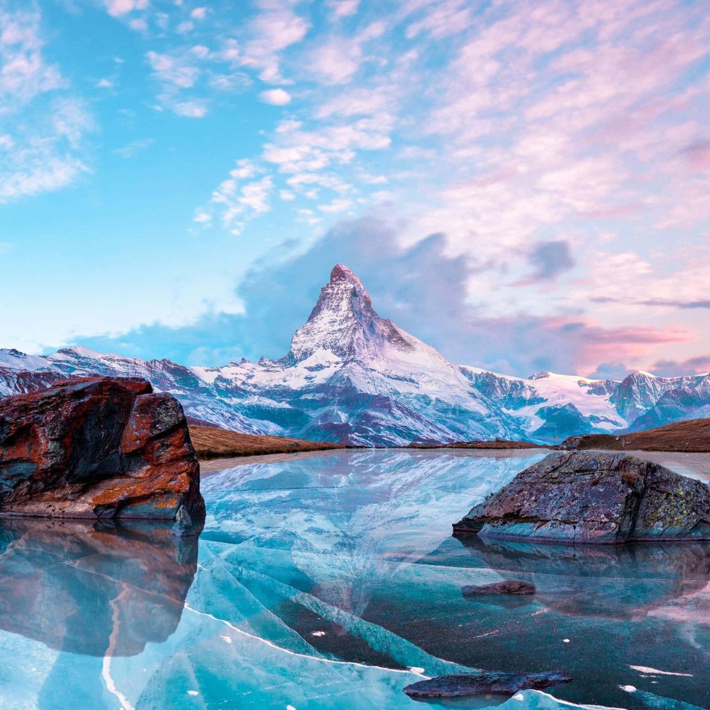 Matterhorn peak reflected on cracked frozen lake with pastel sky winter Alps landscape wallpaper