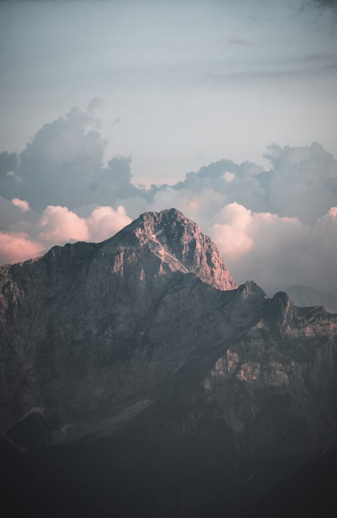 Majestic mountain landscape with rugged rocks pink light dramatic clouds and serene sky background Wallpaper