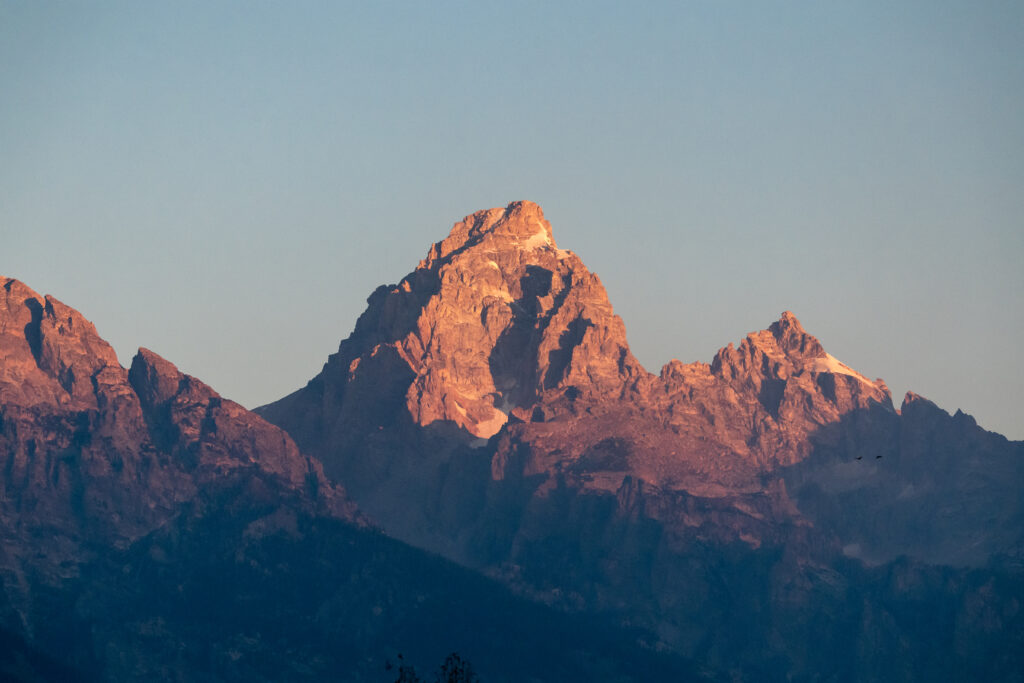 Majestic sunlit mountain landscape with rugged peaks and layered rock formations background Wallpaper