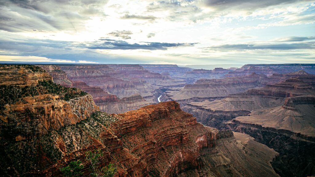 Rugged rocky mountains with deep canyons and layered stones under expansive natural sky Wallpaper