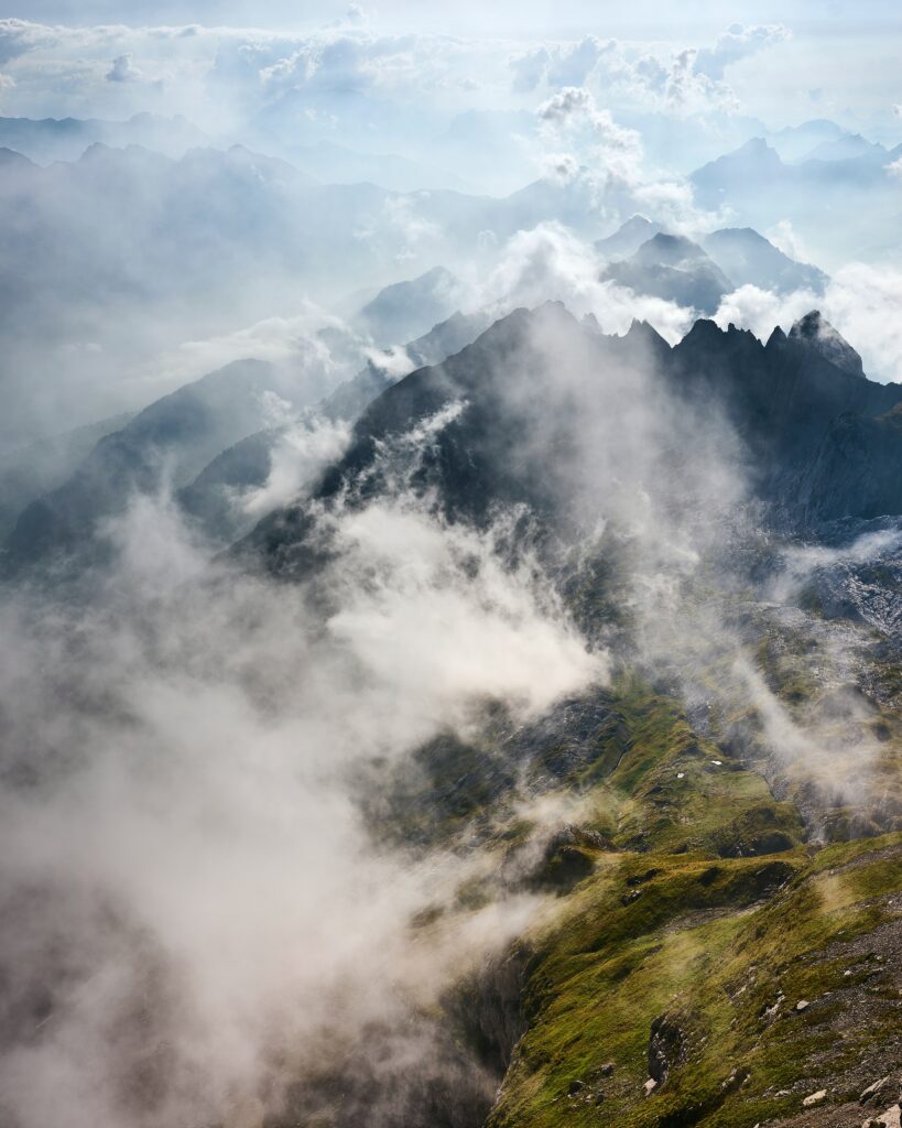Breathtaking mountain landscape with rugged rocks lush grass dramatic clouds and swirling fog Wallpaper
