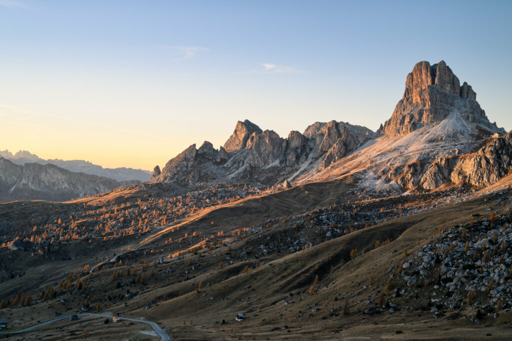 Mountain landscape wallpaper with rugged rocks steep slopes sparse trees warm evening light