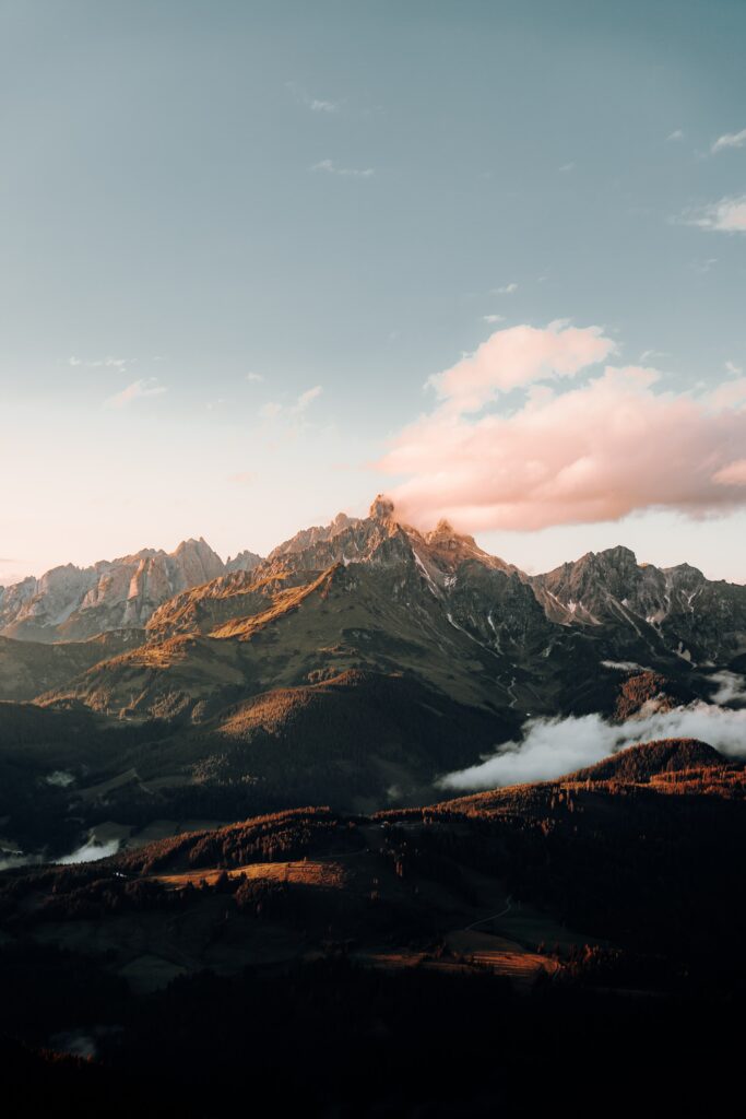 Majestic mountain peaks with rugged rocks in golden light and swirling fog natural wallpaper