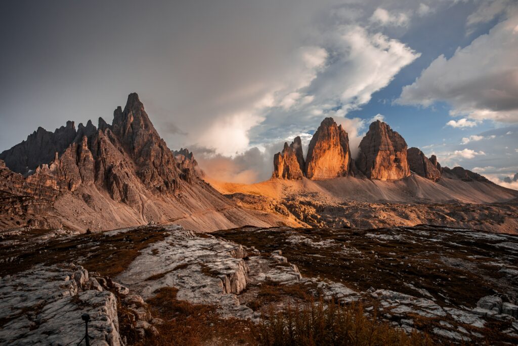 Majestic rugged mountains with warm sunlight under dramatic sweeping clouds natural landscape wallpaper