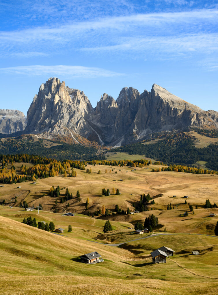 Majestic mountain range above rustic village cottages and golden valley under vibrant blue sky Wallpaper