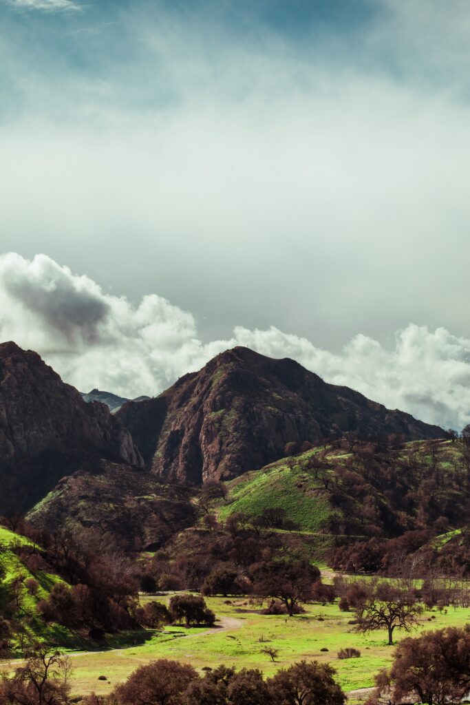 Majestic mountain range with rugged peaks lush green plateau and dramatic cloudy sky wallpaper background