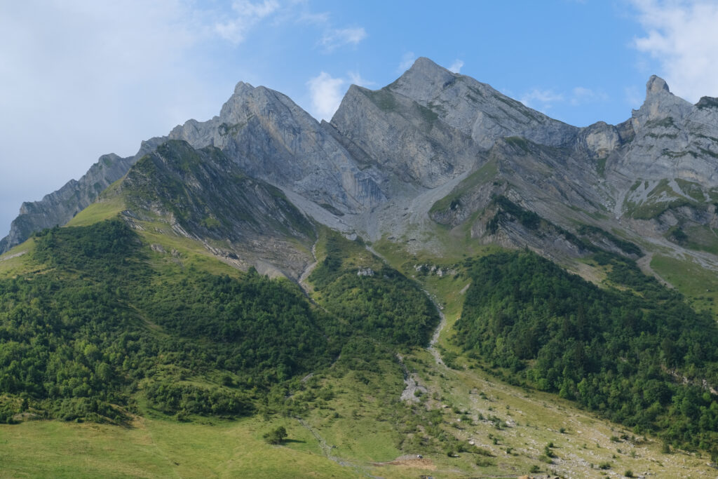 Majestic mountain range with rugged rocks lush green trees and clear blue sky landscape wallpaper