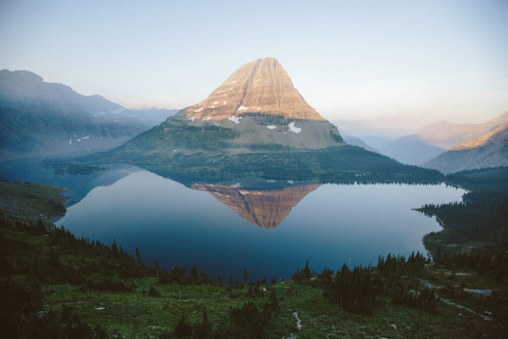 Majestic mountain reflected in calm lake with soft sunlight serene nature wallpaper background