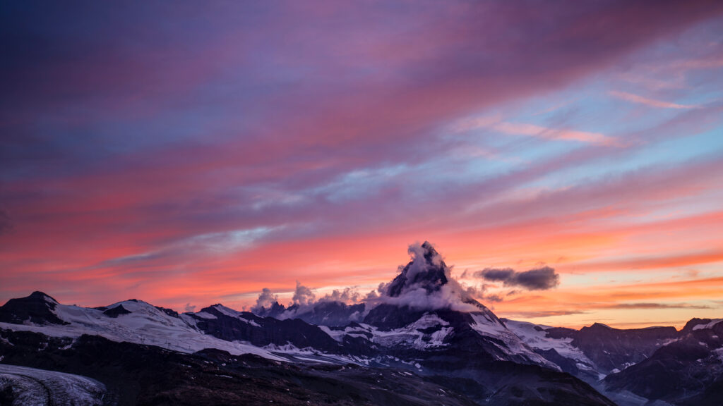 Majestic mountains with fog and colorful sunset clouds in orange pink and purple wallpaper background