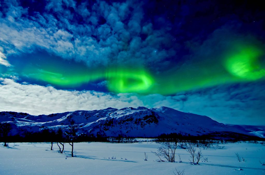 Aurora Borealis over snowy mountains under dramatic night sky Northern Lights wallpaper background