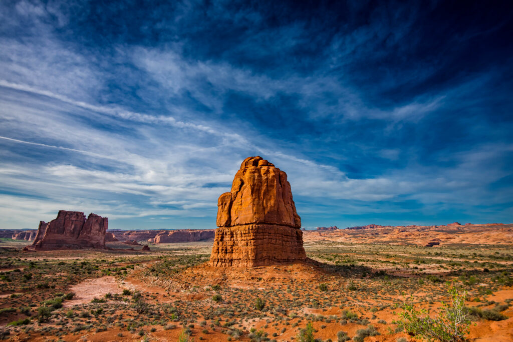 Majestic rock formation in rugged mountain valley under dramatic blue sky wallpaper background