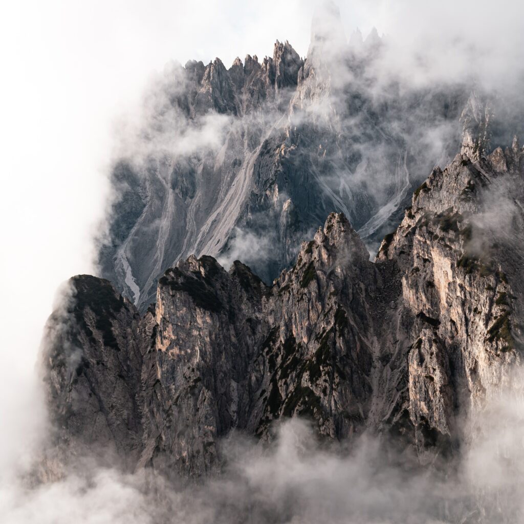 Dramatic rocky mountain peaks rising through swirling clouds in a moody majestic landscape Wallpaper