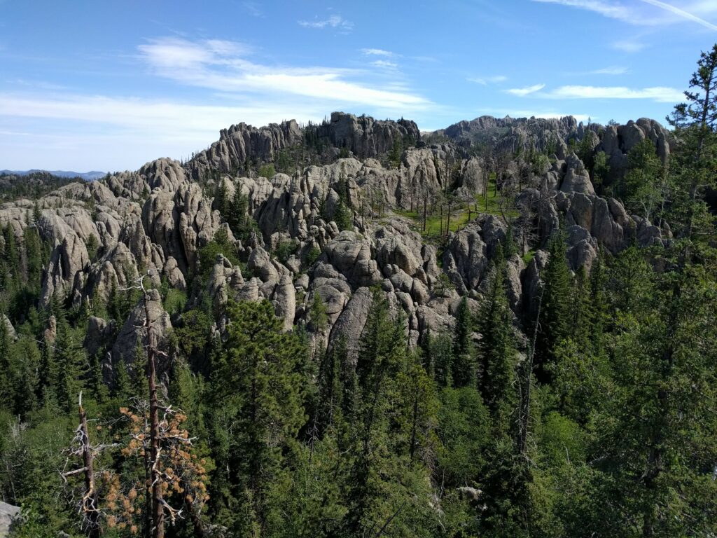 Breathtaking stone formations and lush green forest beneath clear blue sky natural landscape wallpaper