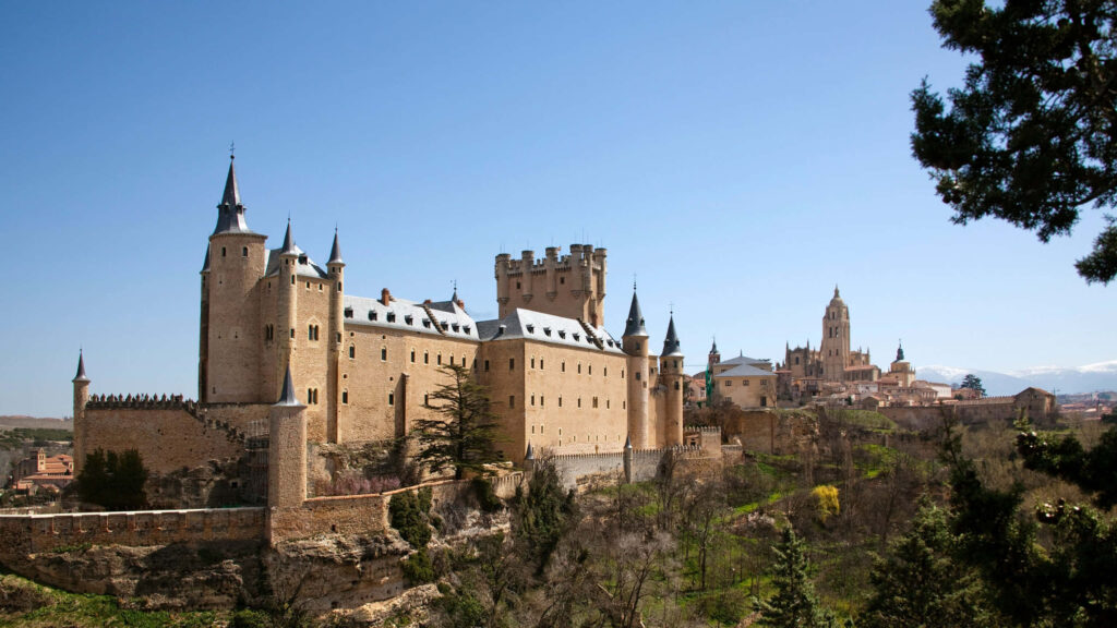Majestic Segovia Castle Wallpaper: Lush Greenery & Clear Sky