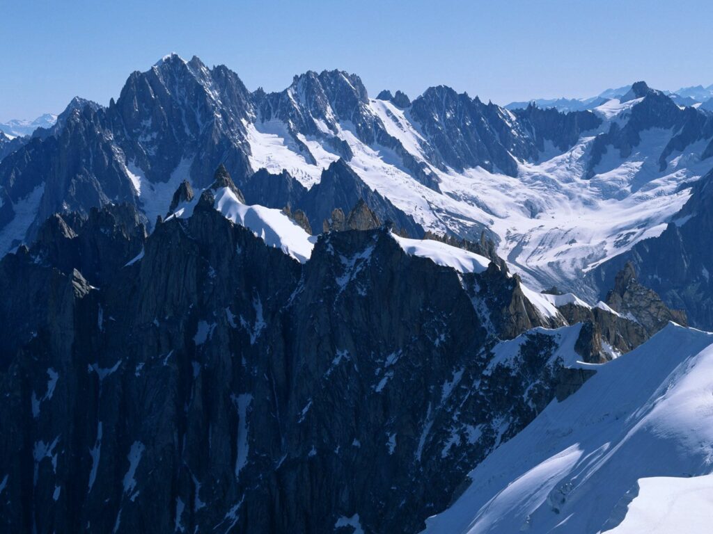 Snow-capped rugged mountains under clear blue sky showcasing majestic natural landscape wallpaper