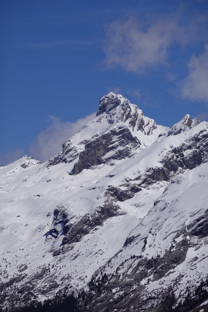 Snow-covered mountain peak with rugged rocks and steep slopes under a bright blue sky winter wallpaper