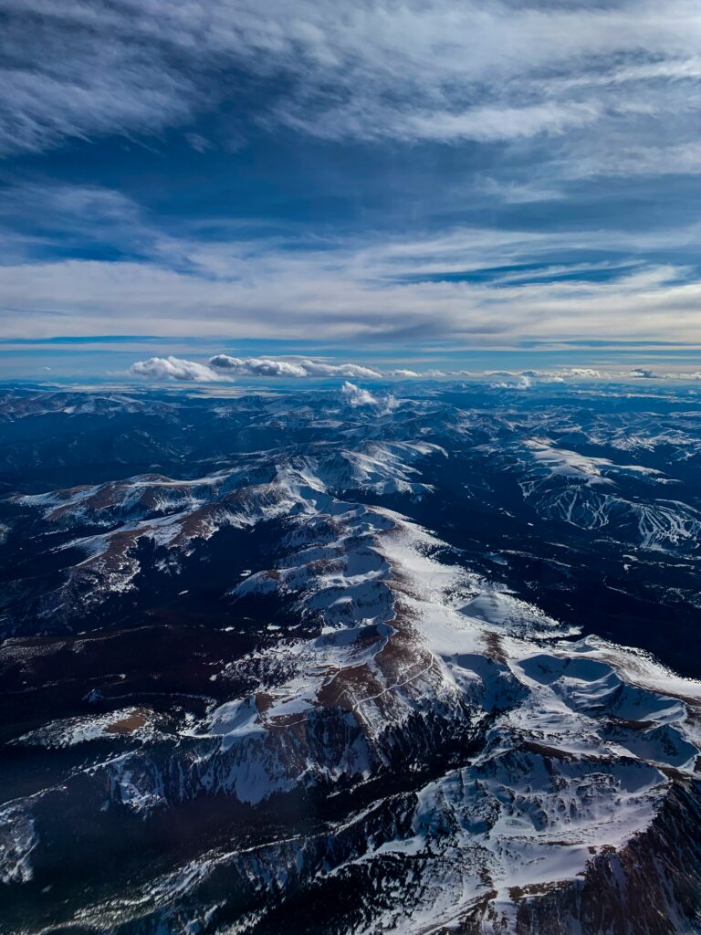 Aerial view of snow-covered mountains under dramatic cloudy sky natural landscape wallpaper