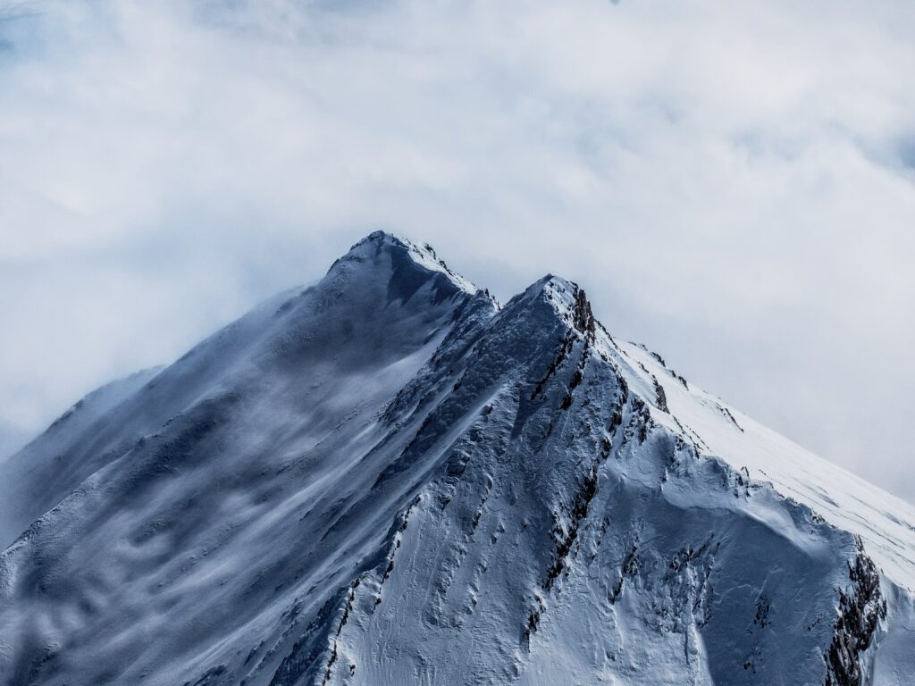 Snowy mountain peaks with rugged ridges and mist in a serene high resolution landscape wallpaper