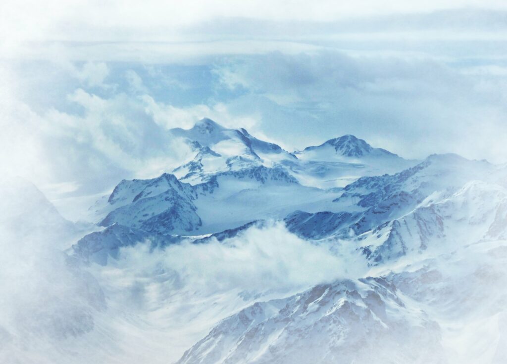 Snow-covered mountains with dramatic clouds create a serene and majestic winter landscape wallpaper