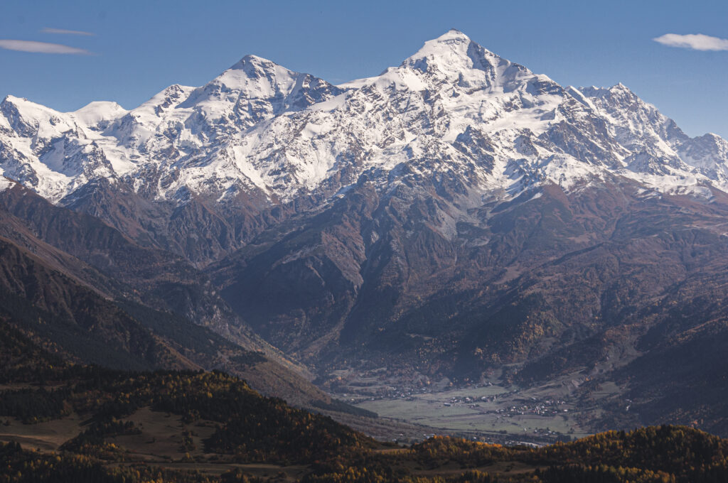 Snowy mountain peak with rugged rocks and clear blue sky creating a tranquil landscape wallpaper
