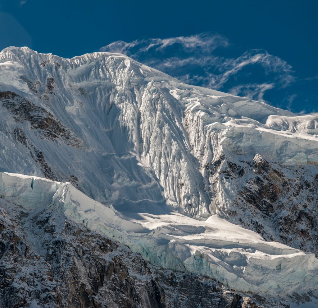 Snow-covered mountain peak with sharp ridges under clear blue sky natural landscape wallpaper
