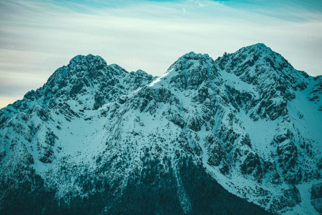 Snow-covered majestic mountain peaks with blue tones and shadows in a serene alpine landscape Wallpaper