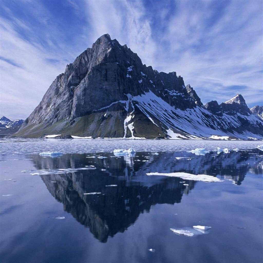 Reflective Wonderland: iPad Pro Wallpaper showcasing a Majestic Snowy Mountain near a Pristine Water Surface