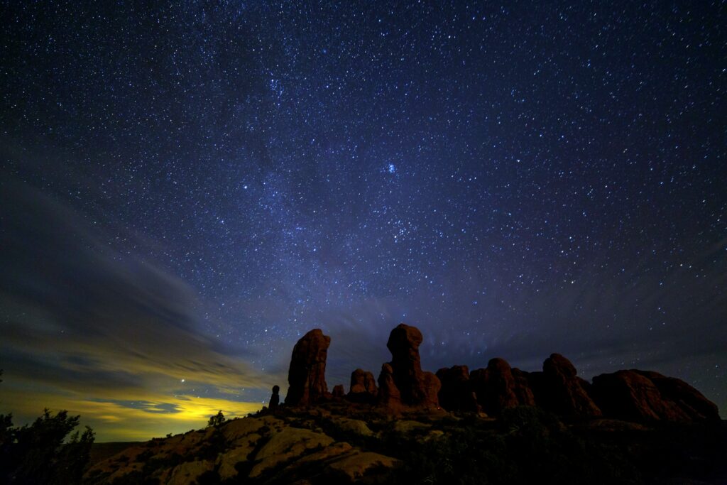 Starry night sky over rugged rock formations with deep blue horizon wallpaper background