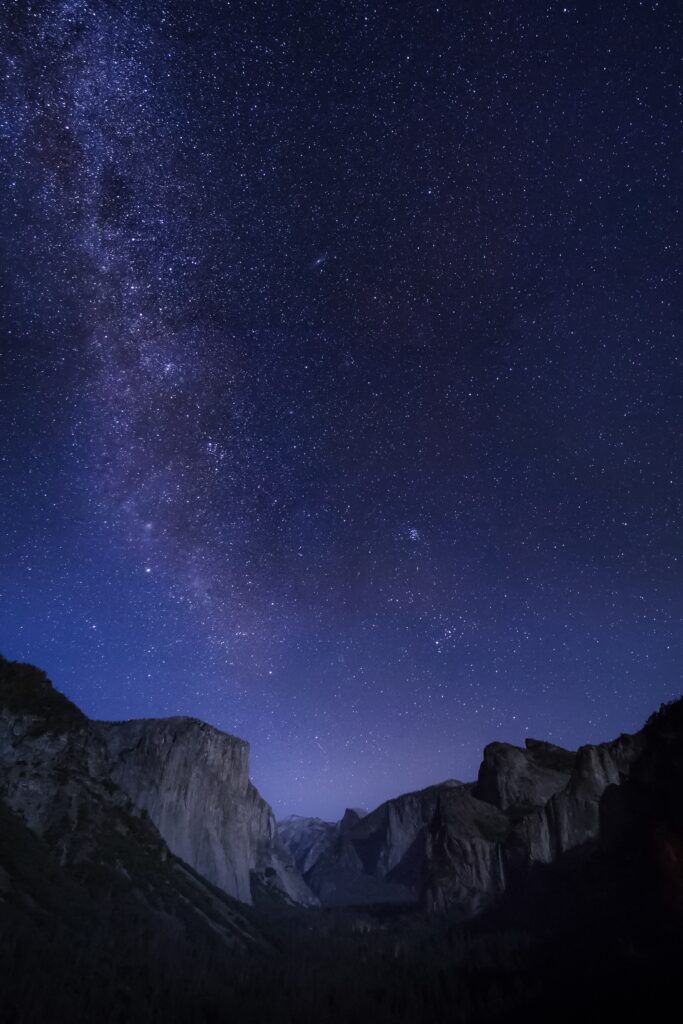 Starry night sky over towering rock formations with deep blue and purple natural landscape wallpaper