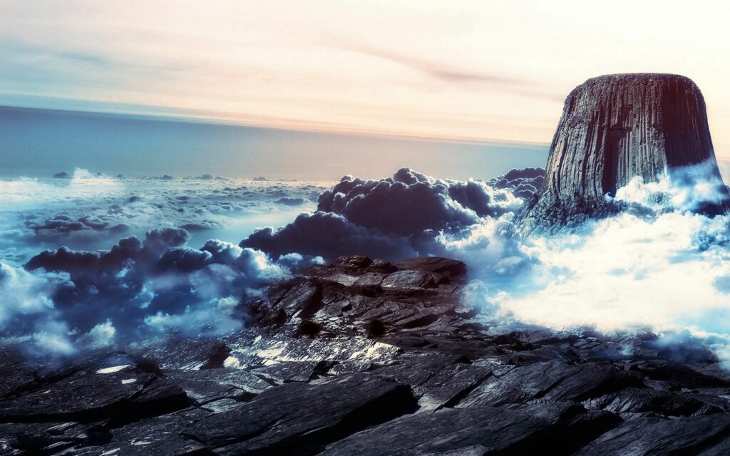 Towering stone mountain ridge above clouds with rugged rocks and pastel sky serene landscape wallpaper
