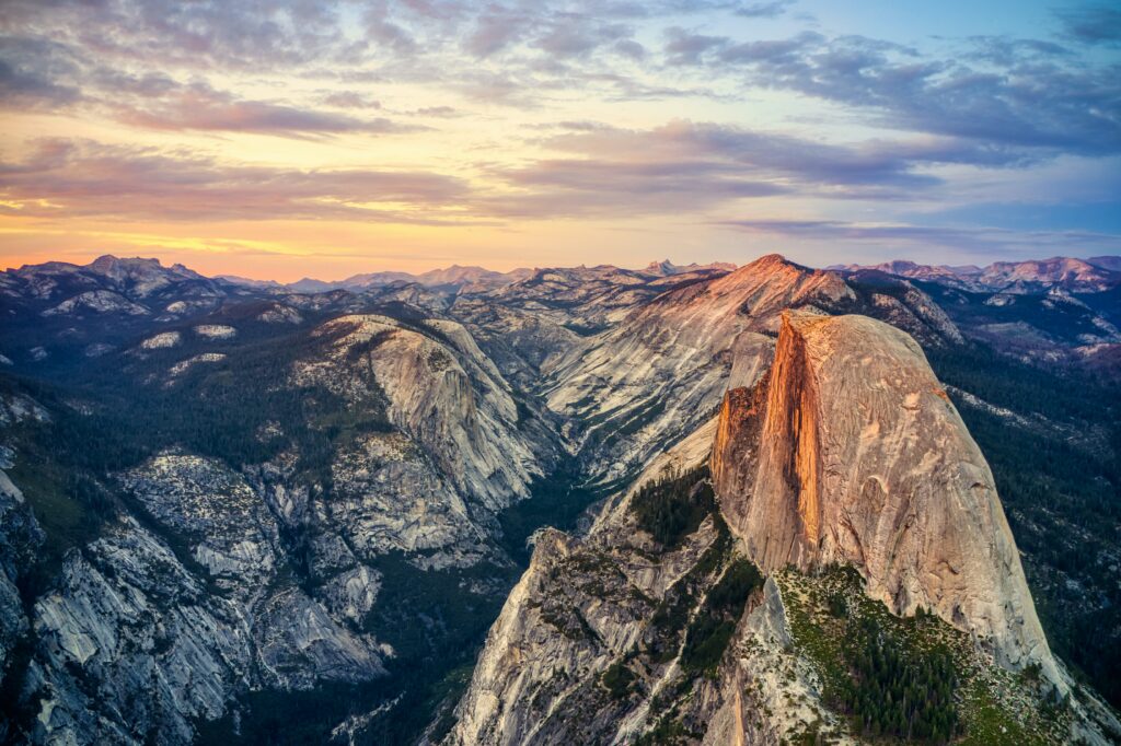 Sunset over rugged mountain peaks and layered rocky valley in a dramatic wilderness landscape wallpaper