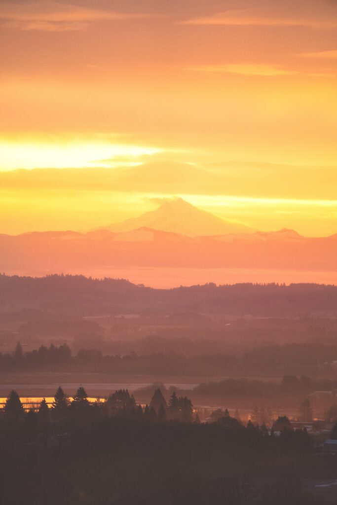 Majestic volcano at sunset with vibrant orange and purple hues over distant mountains wallpaper