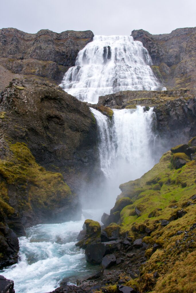 Majestic waterfall cascading over rugged rocks with vibrant blue pools and mossy stones wallpaper
