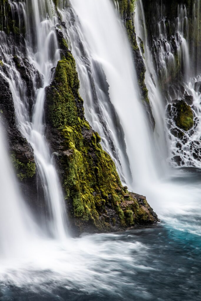 Majestic waterfall over mossy rocks with silky streams flowing into a crystal blue pool wallpaper