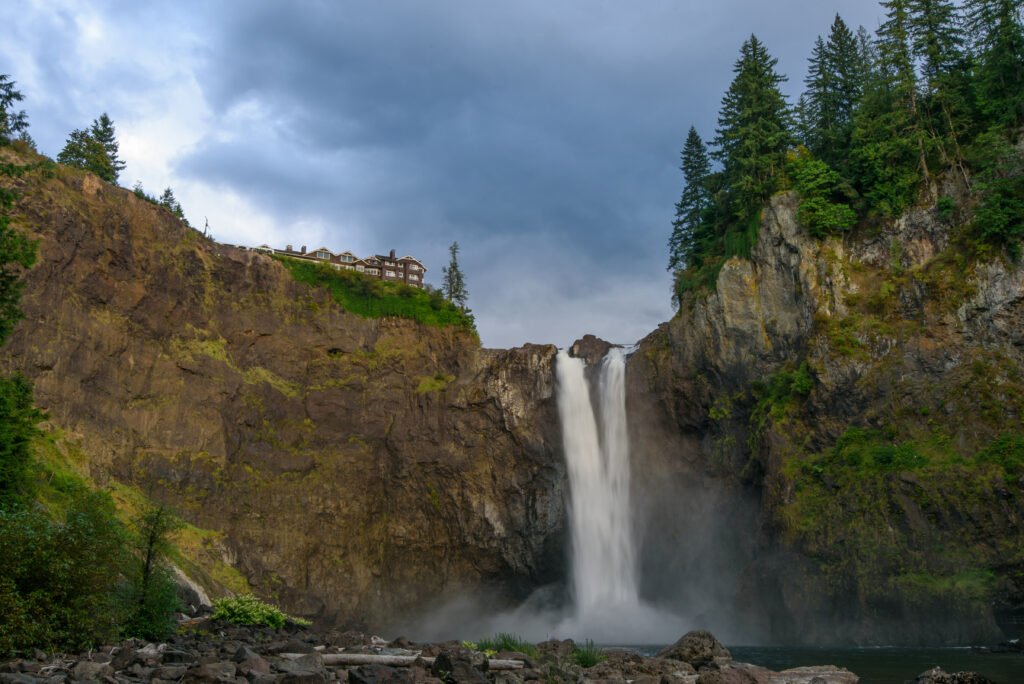 Powerful waterfall cascading over rugged rocks with mist mossy stones evergreen forest cliffs Wallpaper