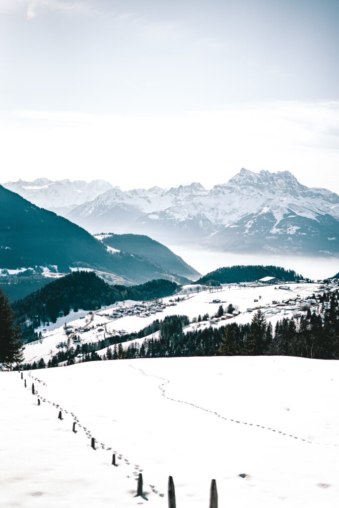 Winter alpine landscape with snow-covered fields mountains and rugged rocks under clear sky Wallpaper