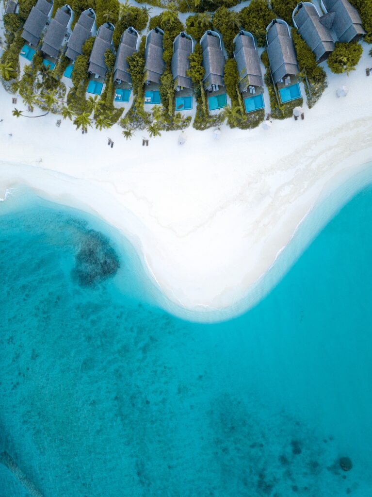 Aerial view of Maldives coastline turquoise waters white sand beach and luxury villas paradise retreat Wallpaper