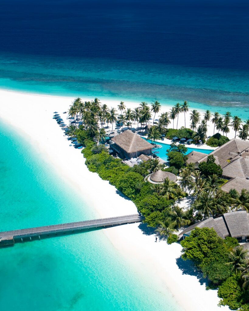Aerial view of Maldives island with turquoise ocean white sand beach palm trees and beach houses Wallpaper