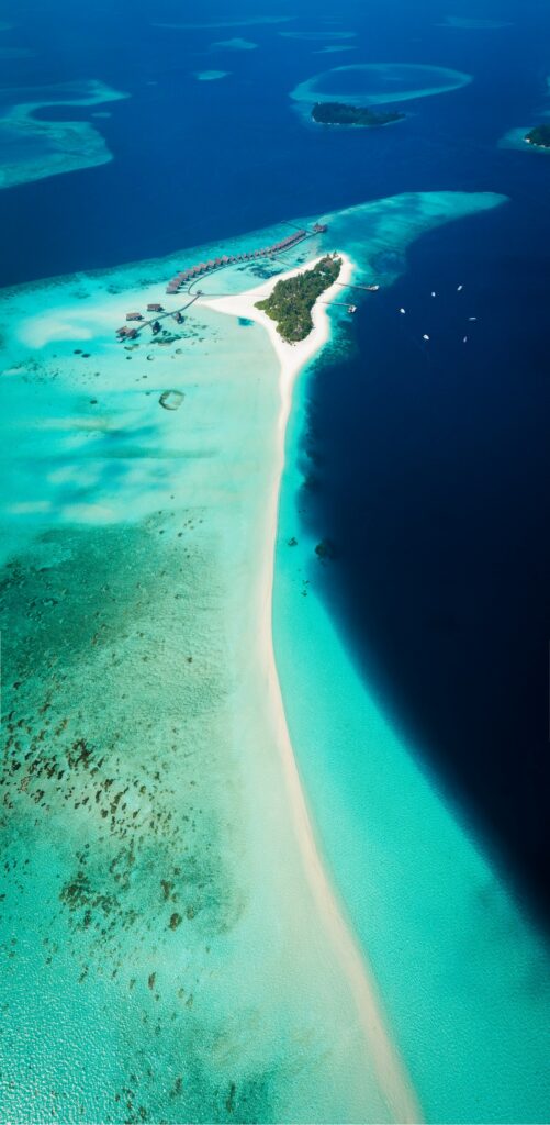 Top view of Maldives island with turquoise waters sandy beaches lush greenery and overwater villas Wallpaper