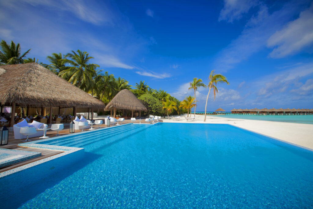 Maldives tropical paradise with crystal pool thatched villas palm trees and turquoise ocean view Wallpaper