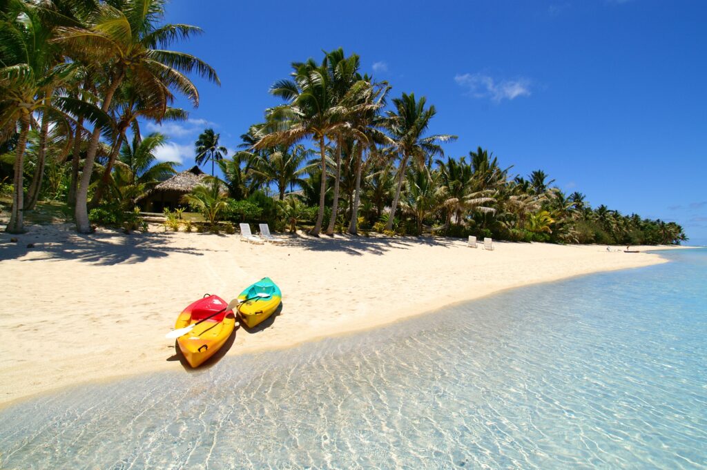 Maldives tropical beach with turquoise water golden sand palm trees and colorful boats under blue sky Wallpaper