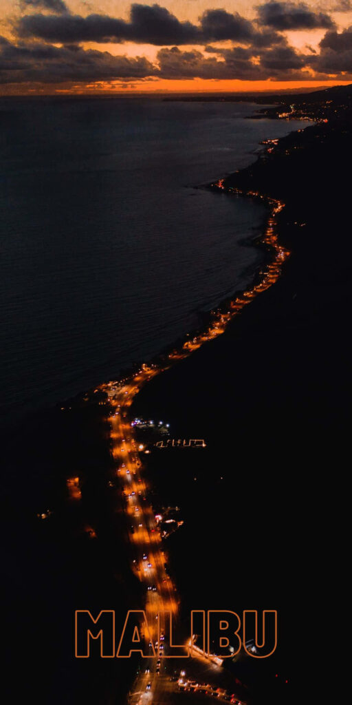 Nighttime Traffic Illuminating Serene Beach Road in Enchanting Malibu Wallpaper
