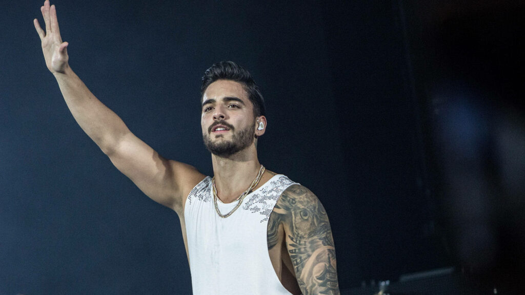 Maluma waving onstage in vibrant live performance wallpaper capturing energetic music vibe