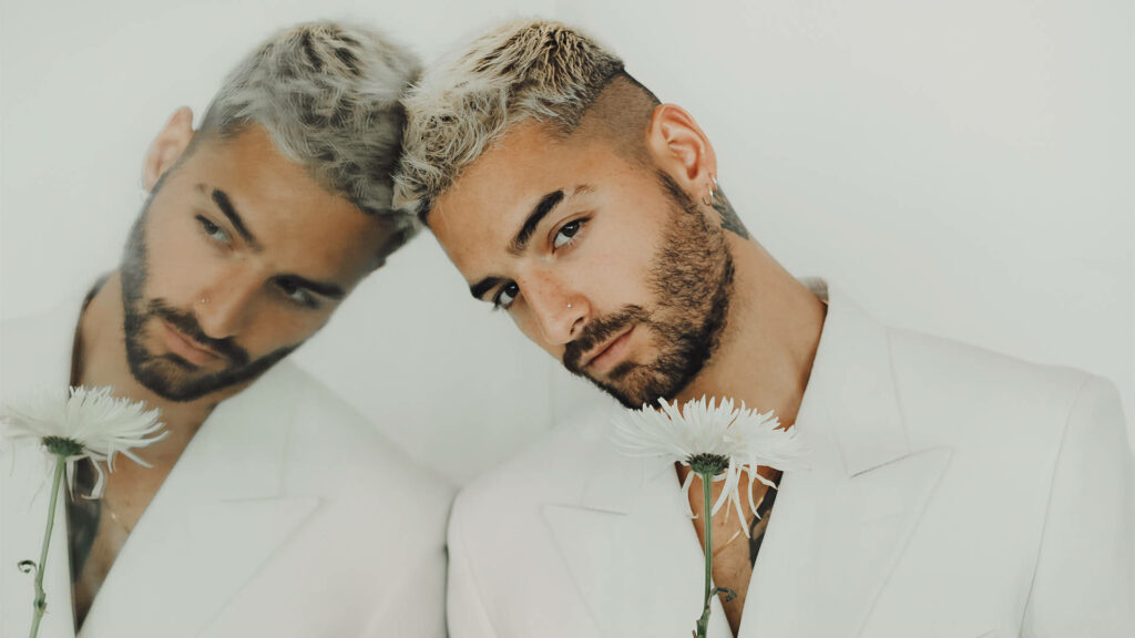 Maluma in white suit holding white flower with soft reflection stylish rapper singer background Wallpaper